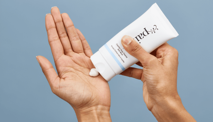 Hands dispensing white cream from Pai Copaiba Deep Cleanse AHA Mask tube for blackhead treatment