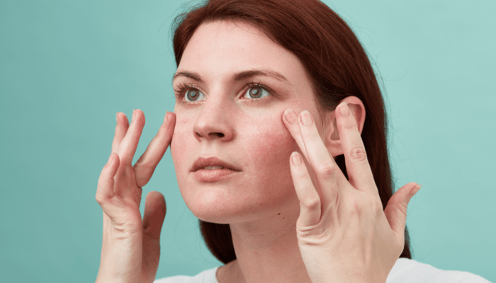 Woman applying Sea Aster & Wild Oat Instant Calm Redness Serum to cheeks with fingertips for sensitive skin