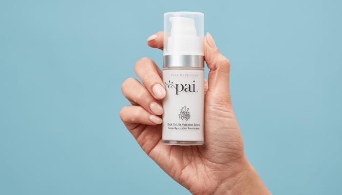 Hand holding Pai Back to Life Hydration Serum for sensitive skin against blue background