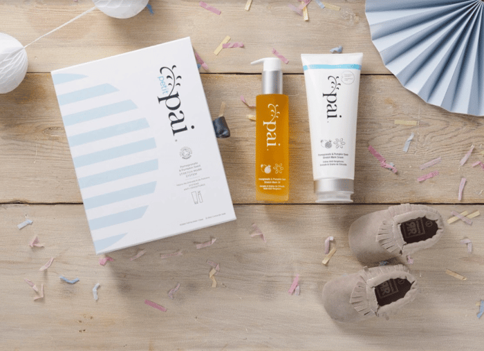 Pai Stretch Mark System gift box with orange stretch mark oil and white cream on wooden surface with party decorations