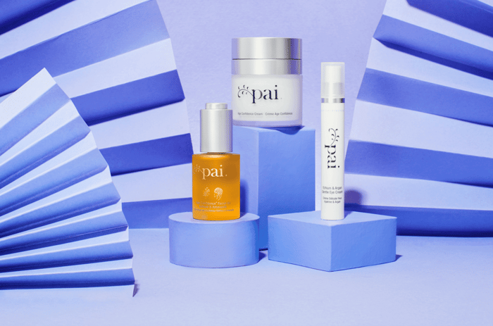Pai Age Confidence skincare collection including oil, cream and eye cream displayed on geometric blue platforms