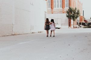 Two women walking hand in hand down an urban street, representing female friendship and solidarity for International Women's Day