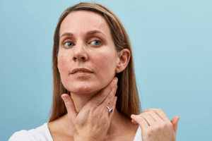 Woman with natural skin examining her face and neck, demonstrating authentic beauty without retouching