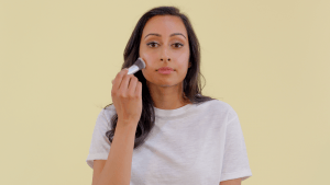 Woman applying Rosehip BioRegenerate Oil as makeup highlighter on her cheekbone for a natural glow