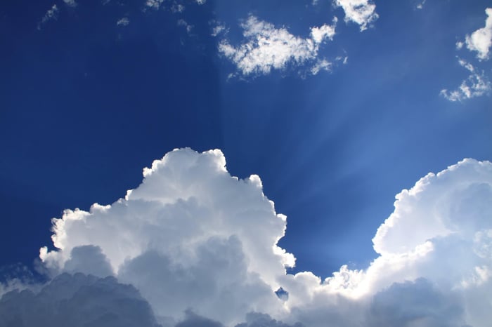 Bright blue sky with fluffy white clouds representing environmental factors that affect skin health