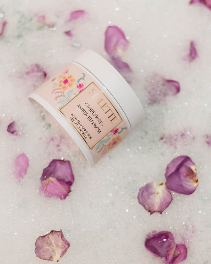 spa night at home with a body scrub sitting in a bubble bath with flowers
