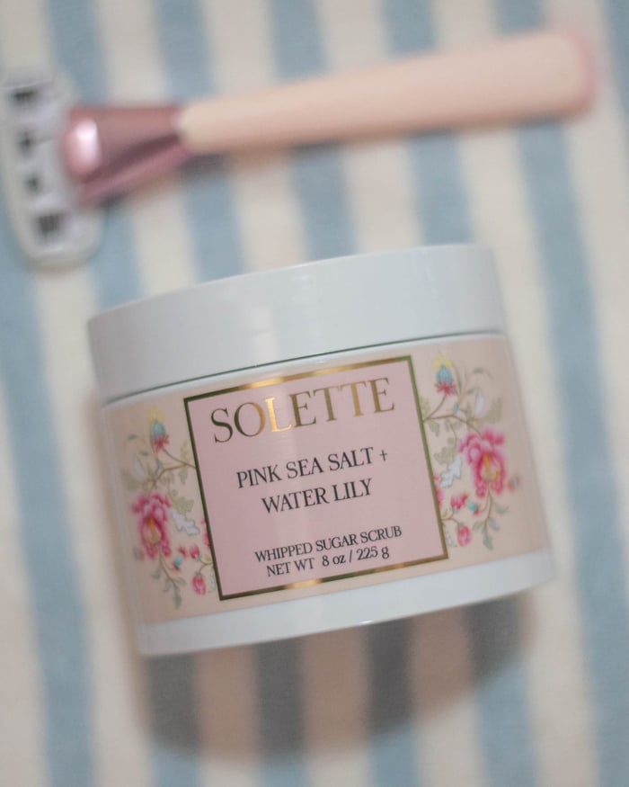 body scrub for shaving pink sea salt with a pink razor on a blue and white towel