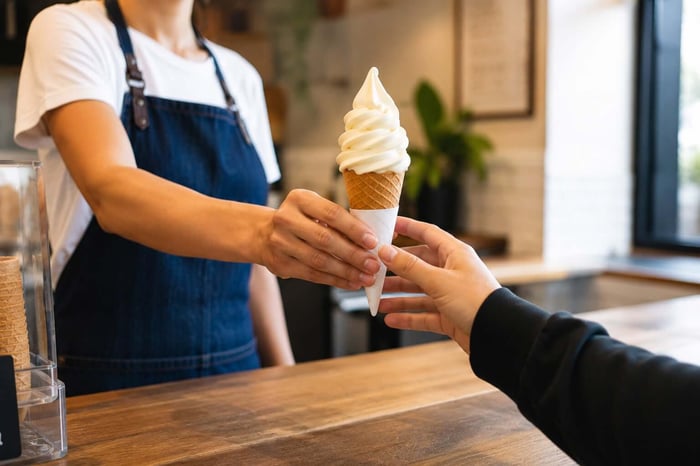 A member of staff handing soft serve ice cream to a customer