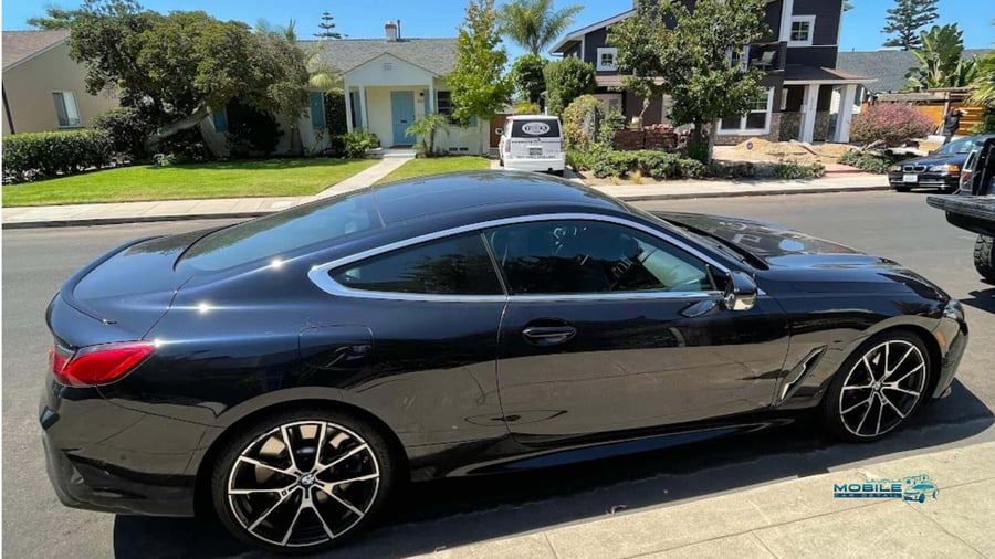 Black BMW 8 Series coupe with mirror-like finish after car wash and wax in sunny San Diego neighborhood