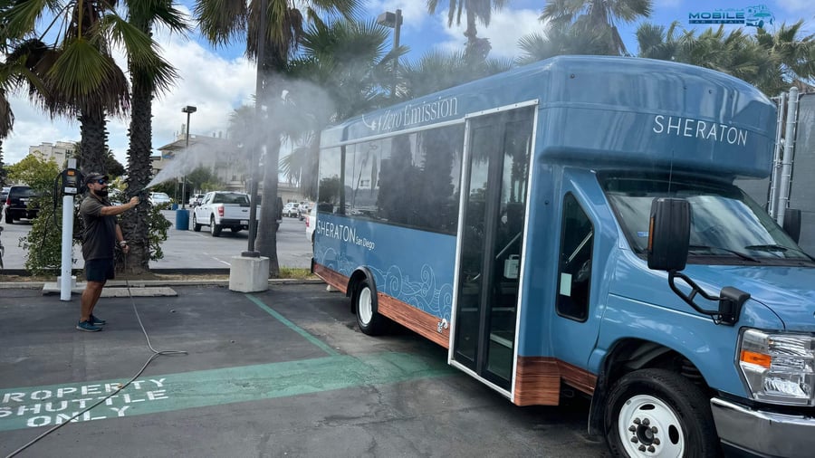 A professional detailer performing high-pressure truck detailing on a Sheraton San Diego zero-emission shuttle bus to maintain a professional fleet appearance.