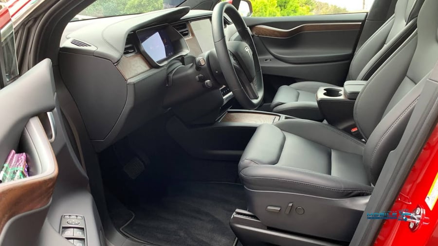 The deep-cleaned interior of a red Tesla in San Diego, showcasing spotless black upholstery and a dust-free dashboard following a professional interior car cleaning service.
