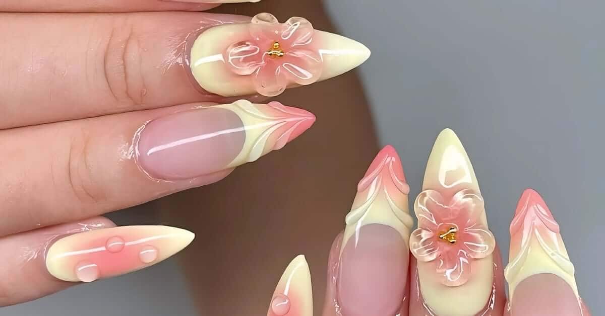 Long 3D acrylic nails feature a pink and yellow marble design with 3D floral art embellishments and raised petal accents.