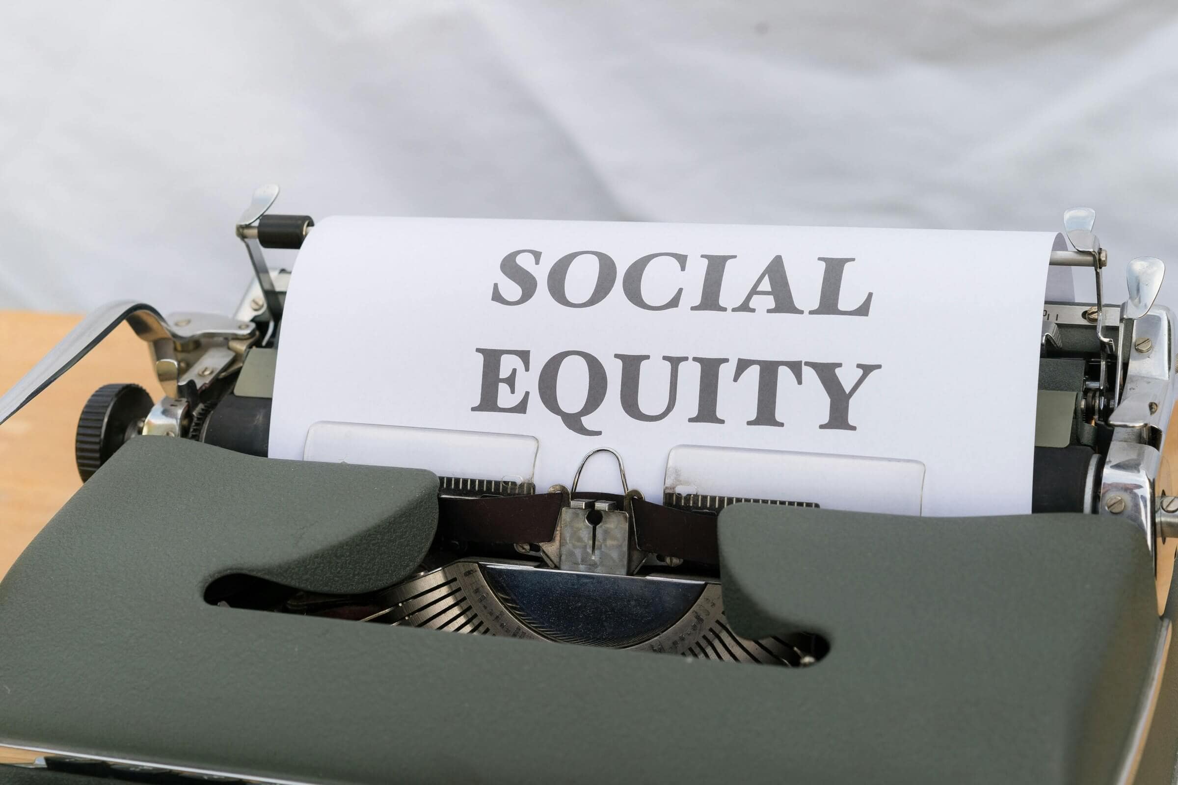 Close-up of a vintage typewriter displaying the message 'Social Equity' on paper.