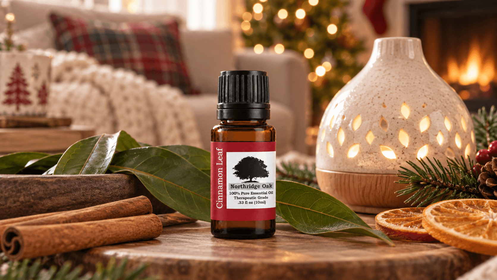 Cinnamon Leaf essential oil beside warm holiday lights, evergreen branches and dried orange on a welcoming seasonal table