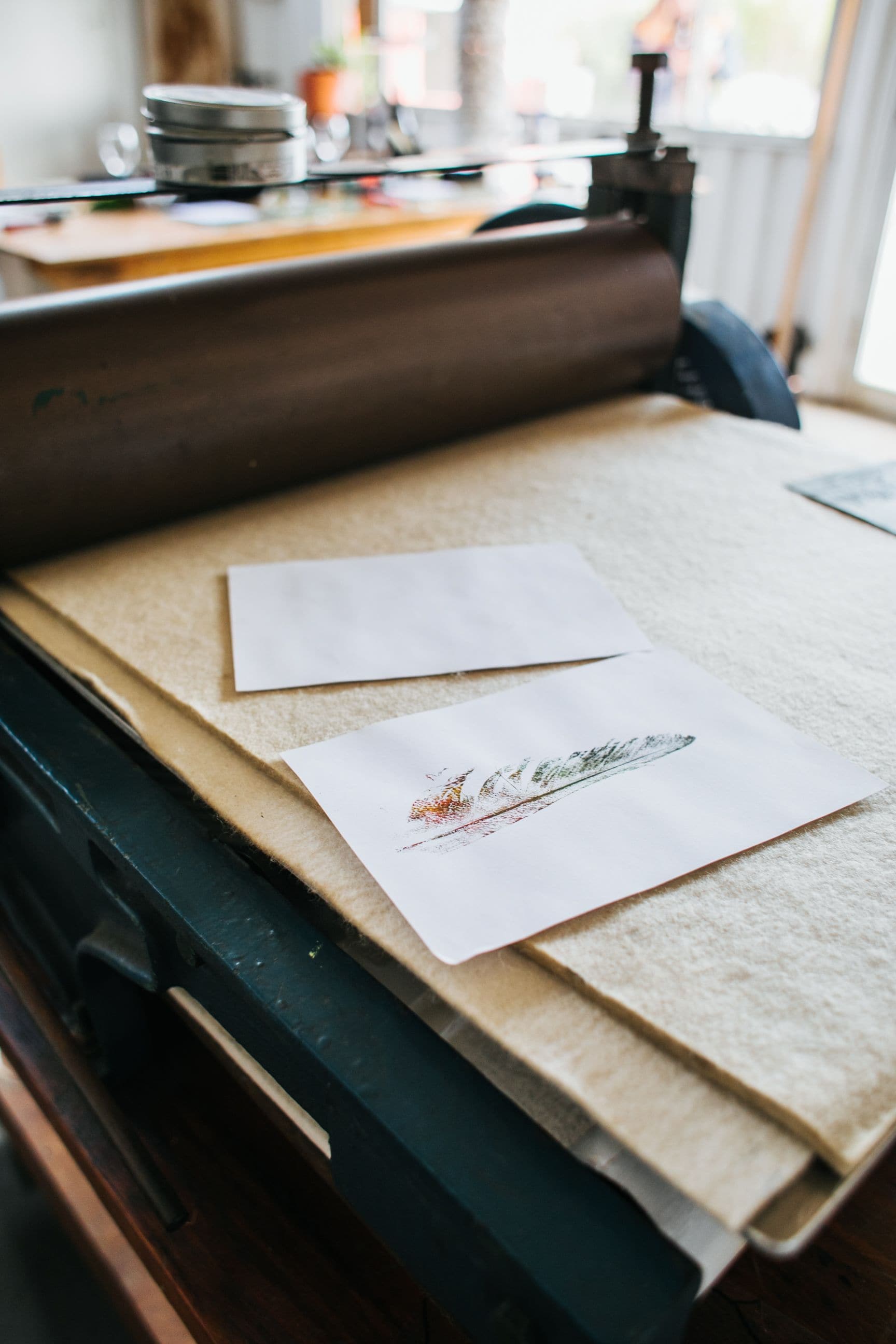 Paper and an art print beside a printing press in a workshop