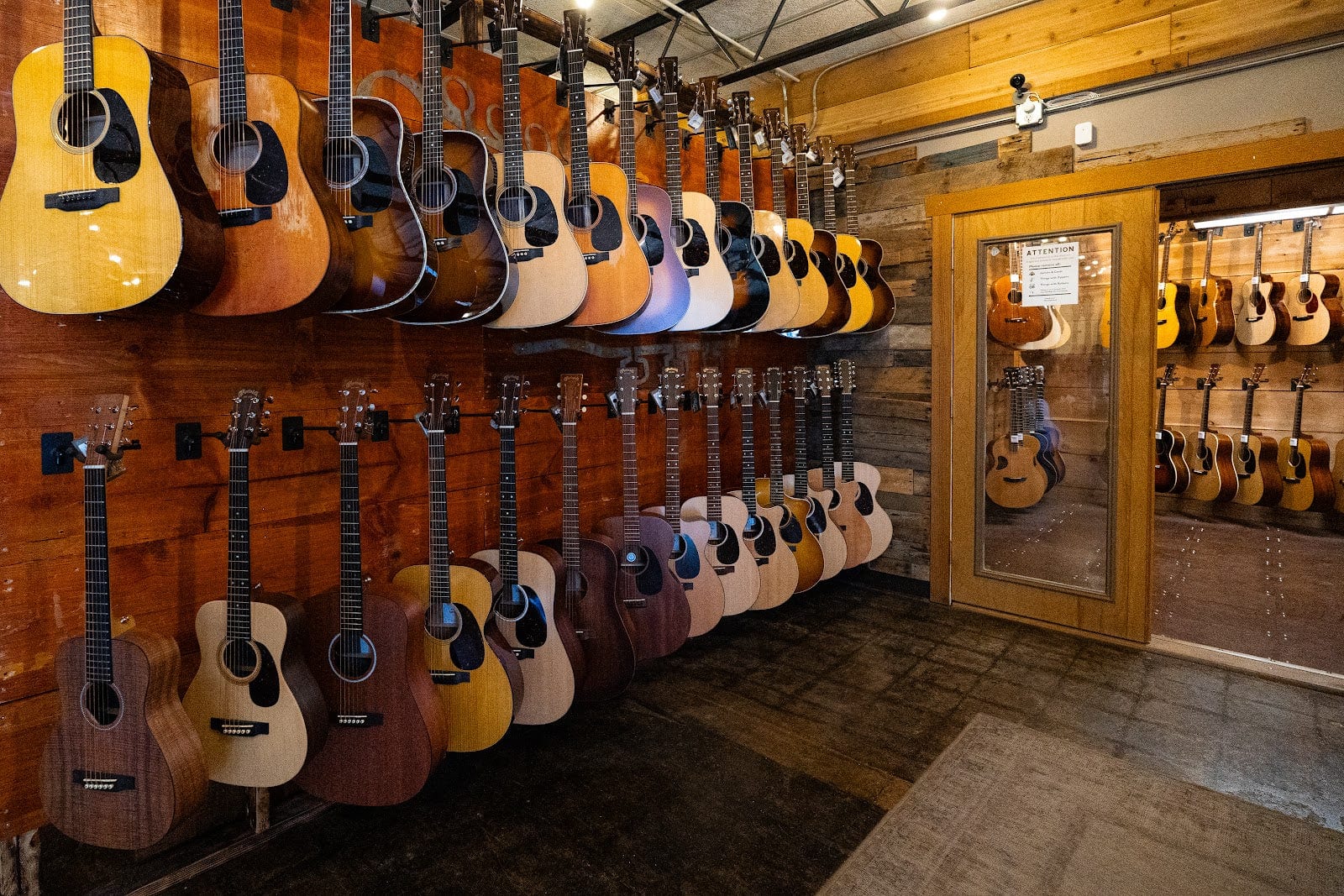 Two-tier wall of acoustic guitars in The Acoustic Shoppe showroom