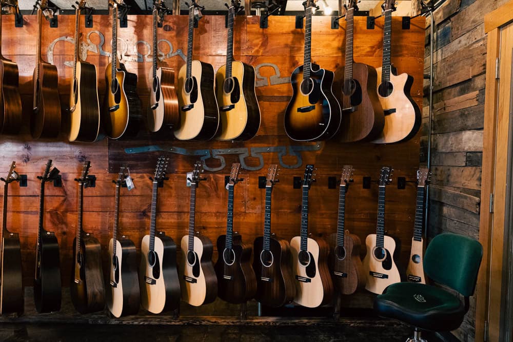 Two rows of acoustic guitars hanging on a wood wall in The Acoustic Shoppe showroom