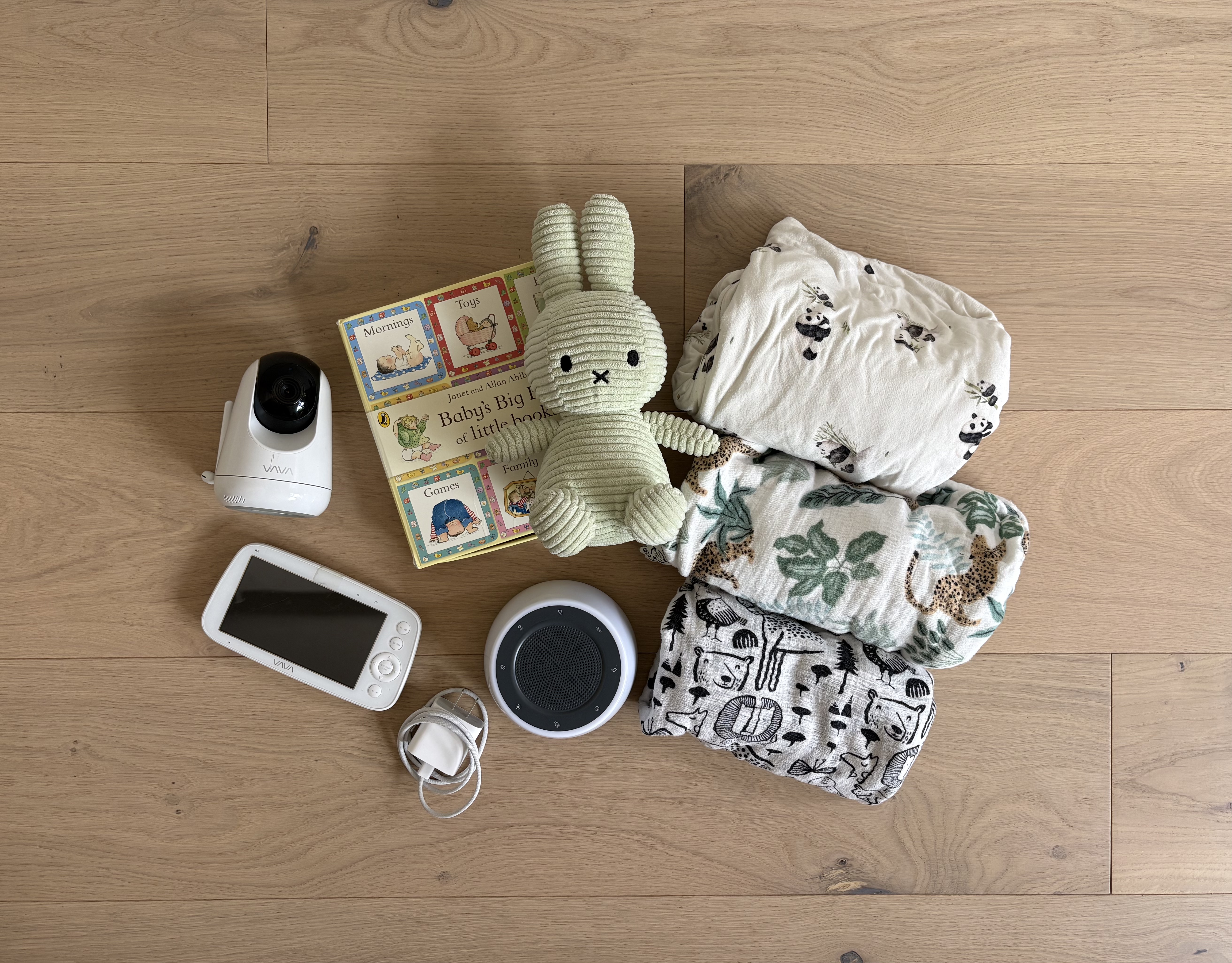 Baby monitor, sound machine, three folded crib sheets, stuffed rabbit and boxed collection of little books