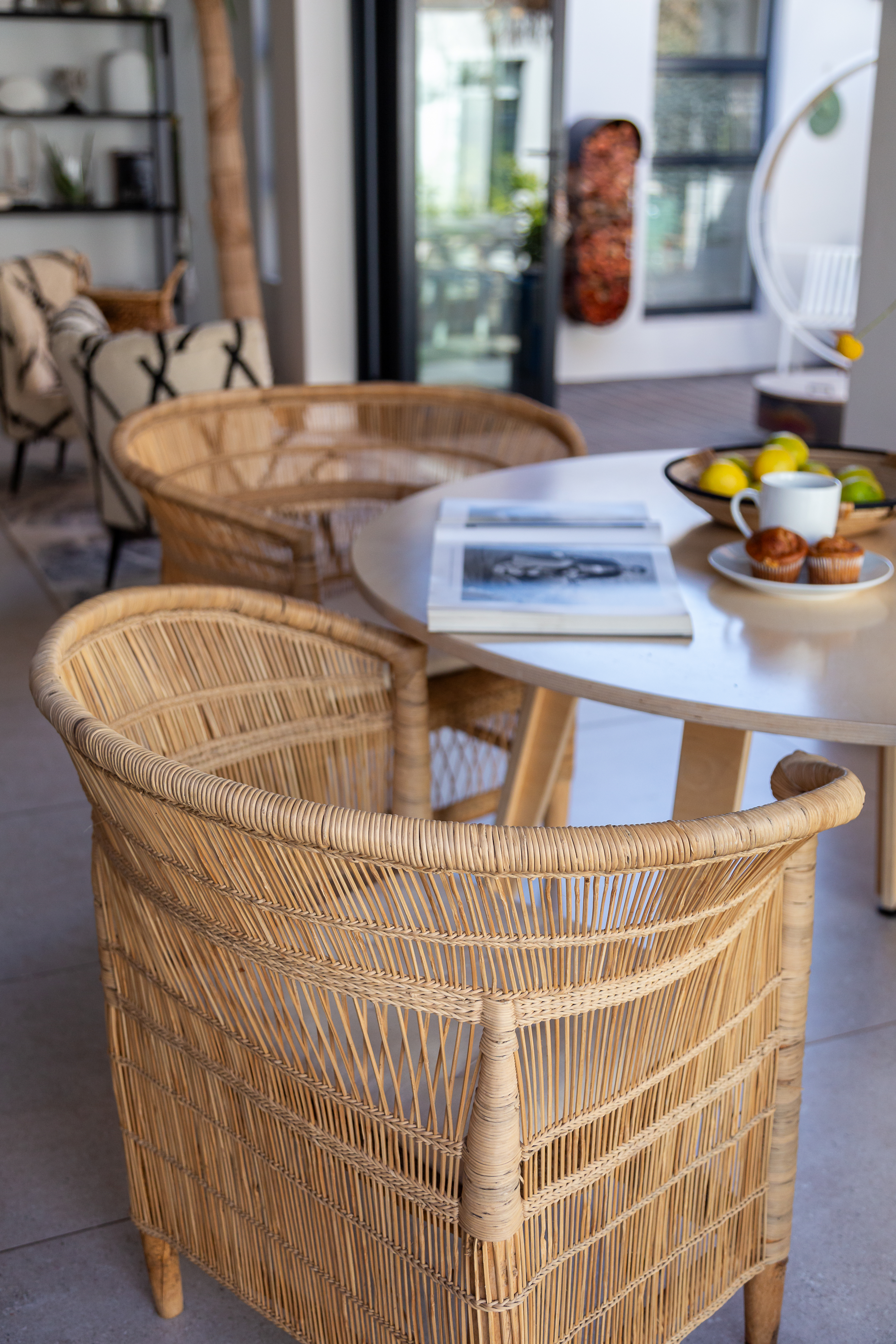 Natural cane dining chairs styled around a round table in a bright, contemporary living space.