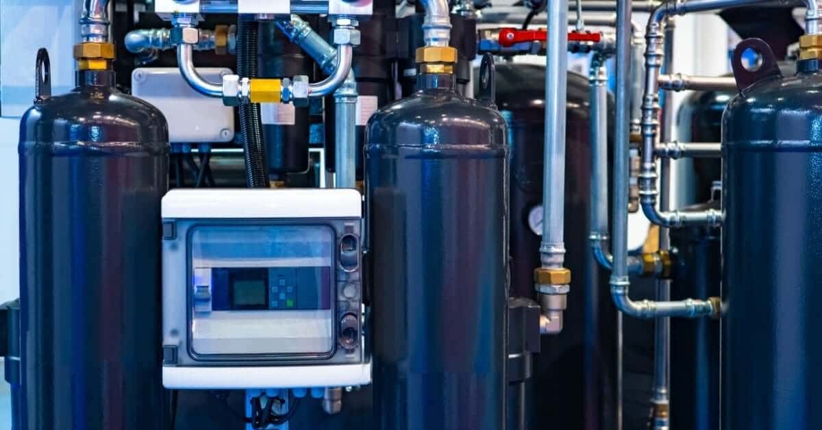 Industrial compressed air system with pressure vessels, gauges, control panel, and interconnected stainless steel piping.