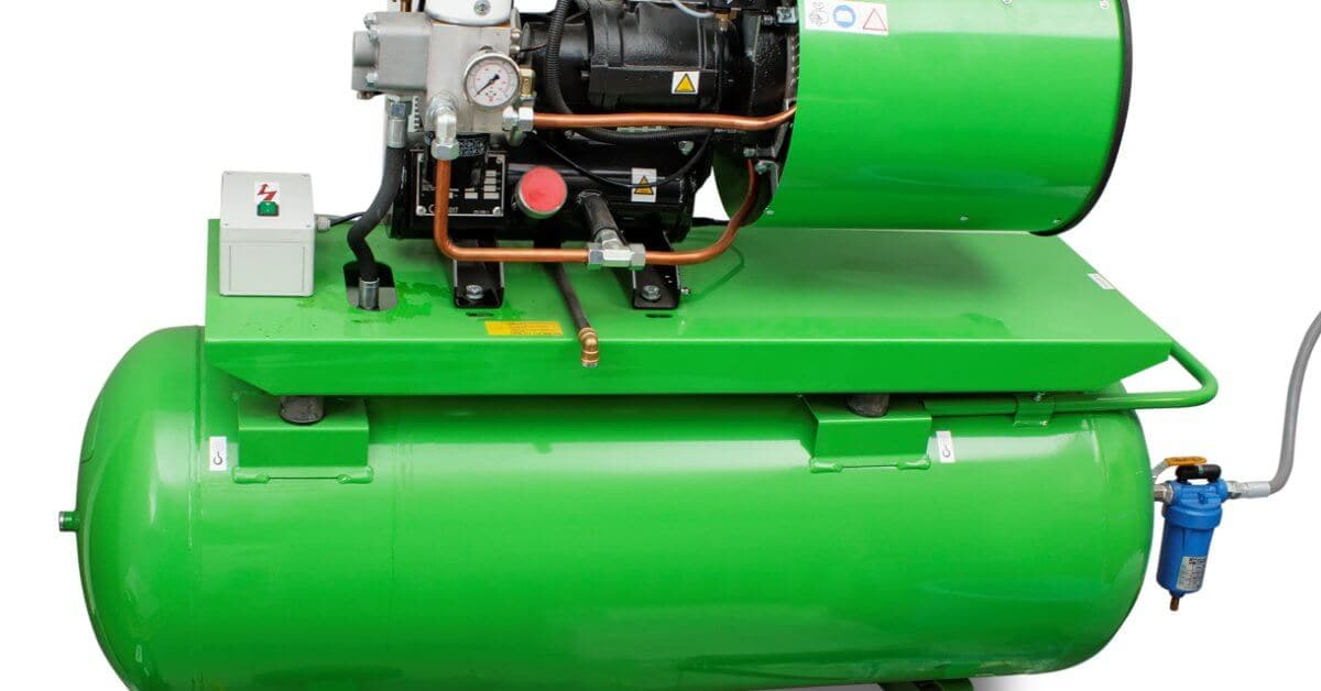 Large green industrial air compressor with a horizontal tank, motor, pressure gauge, piping, filter, and wheels.