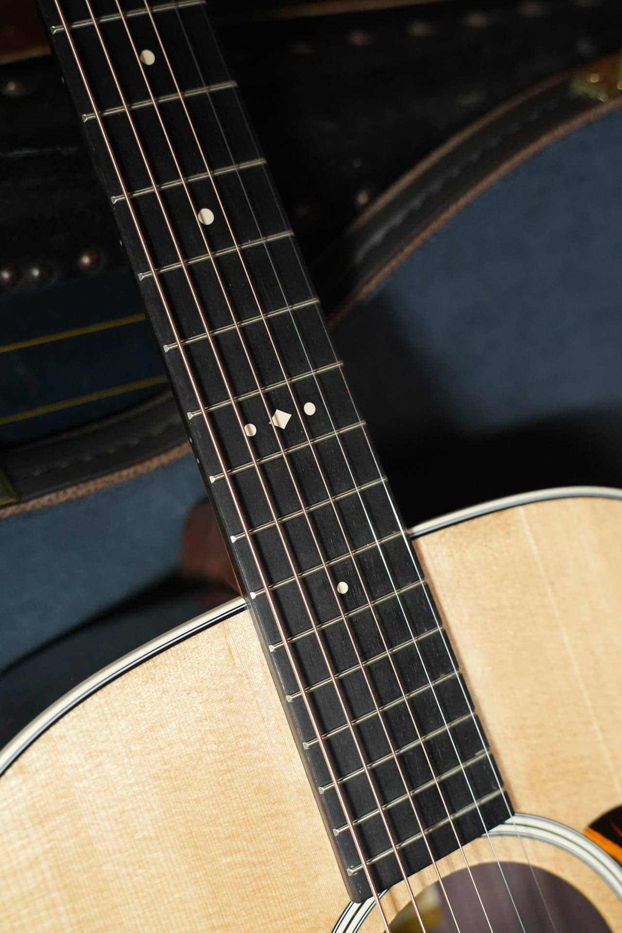 Ebony fretboard of the Taylor 710e with small cream position markers over the spruce top