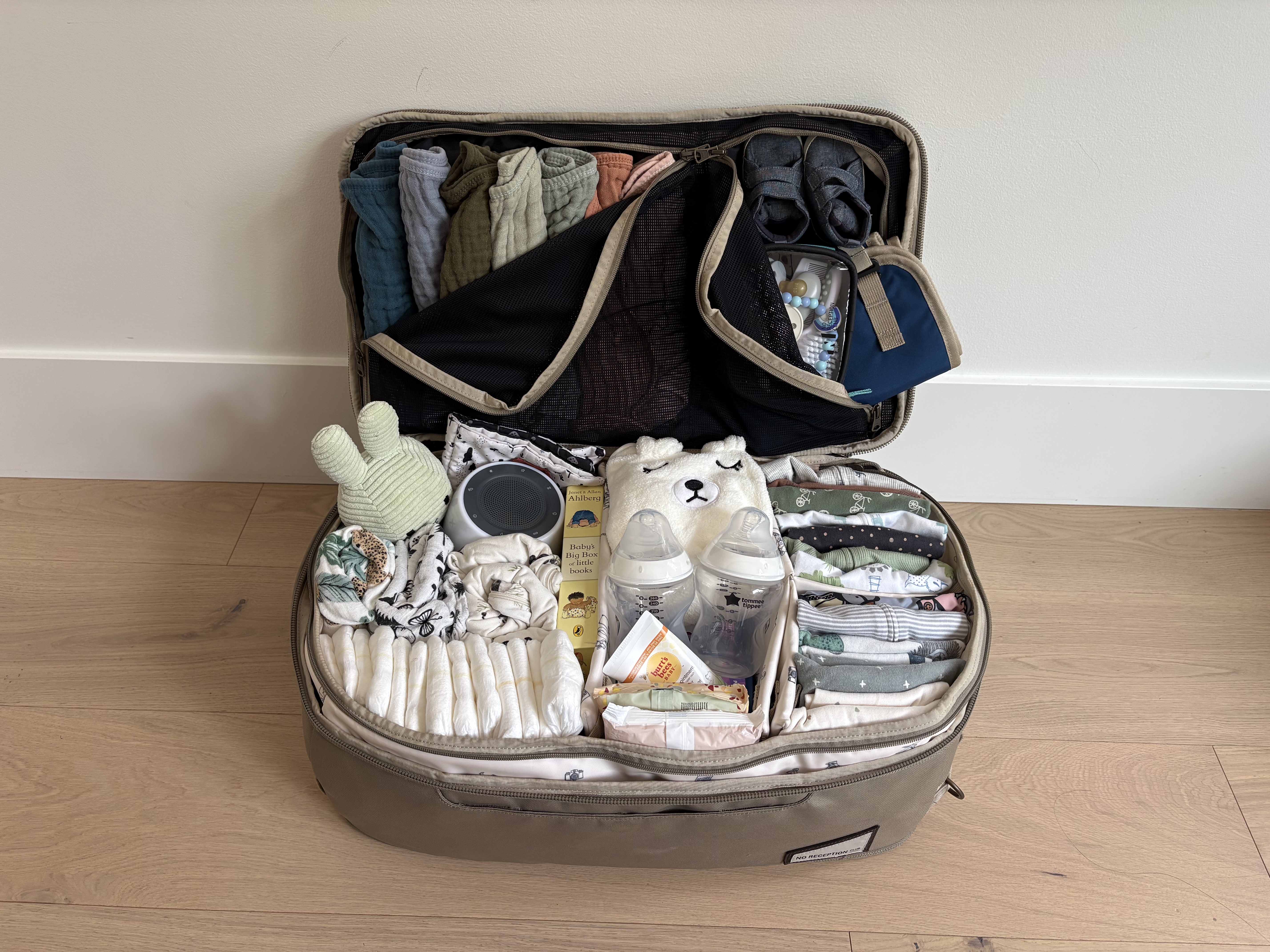 	Baby packing list organized in carry-on luggage, with clothing, diapers, bottles, muslins and bedtime supplies in separate compartments