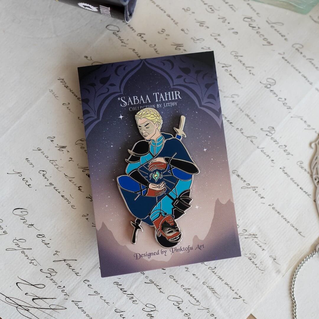 Helene and Avitas Enamel Pin has the two characters in masks appearing as a mirror of each other