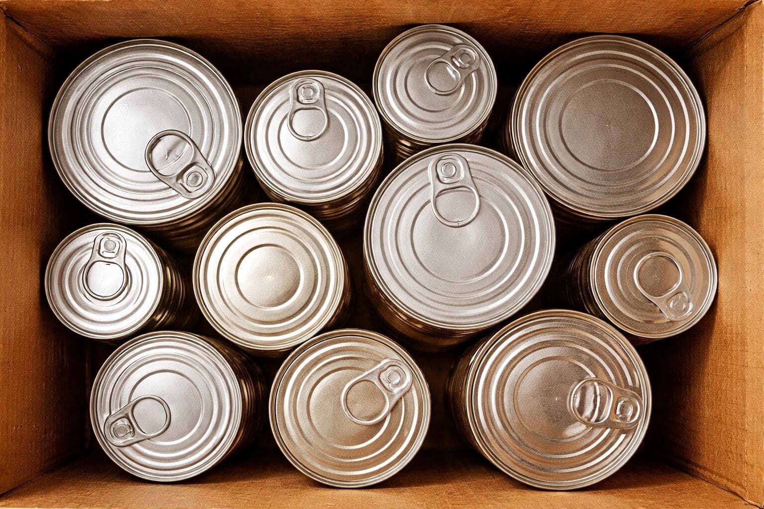 Canned food stacked in a cardboard box for a long term emergency food supply