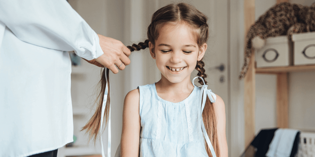 Adult braiding a child's hair.