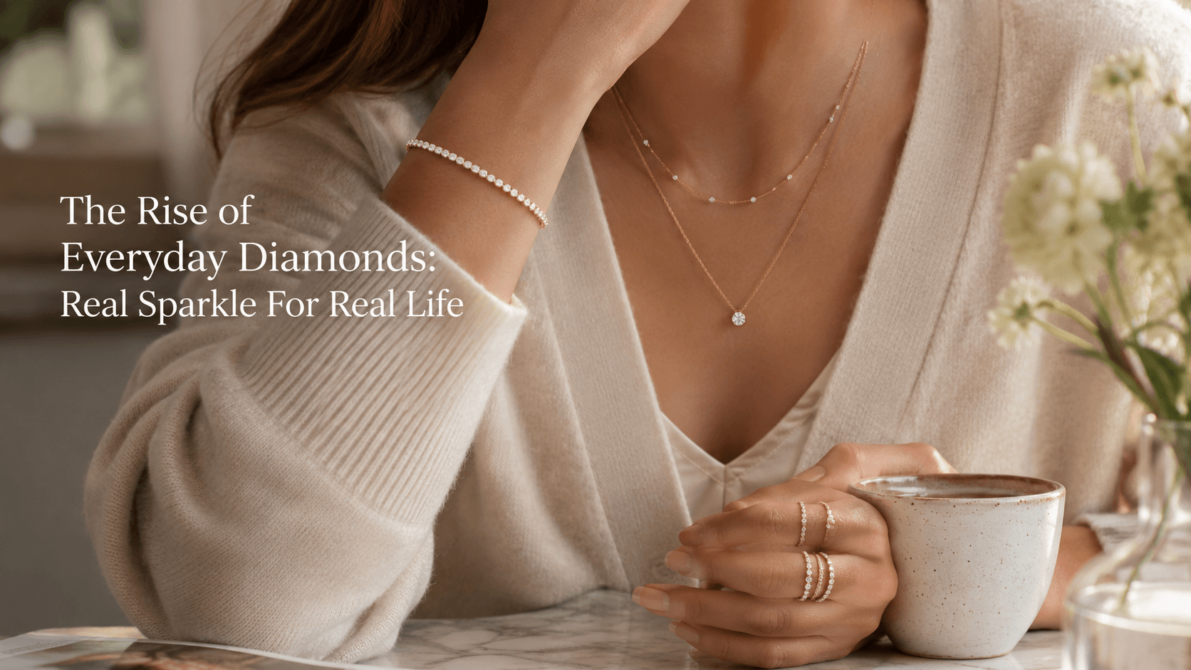 Everyday diamond jewellery worn with soft neutral clothing, showing layered necklaces, rings and a delicate bracelet.