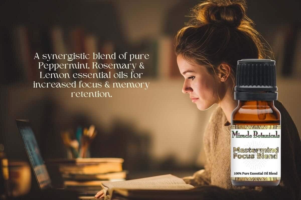 a woman studying in front of her computer with open books by her side, with an amber bottle of Mastermind Focus Essential Oil Blend by Miracle Botanicals, text "A synergistic blend of pure Peppermint, Rosemary, and Lemon essential oils for increased focus and memory retention"