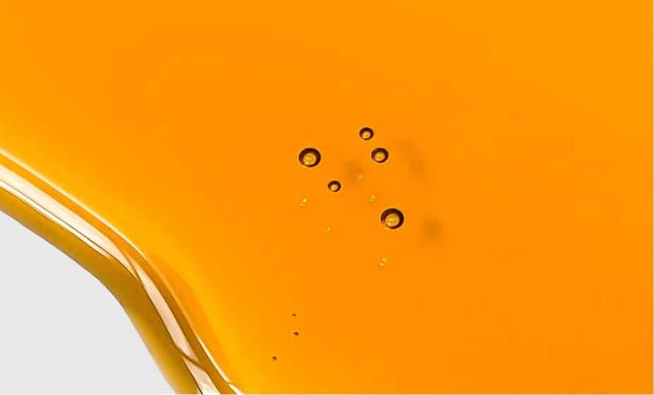 Golden amber rosehip oil with circular bubbles suspended in rich orange liquid
