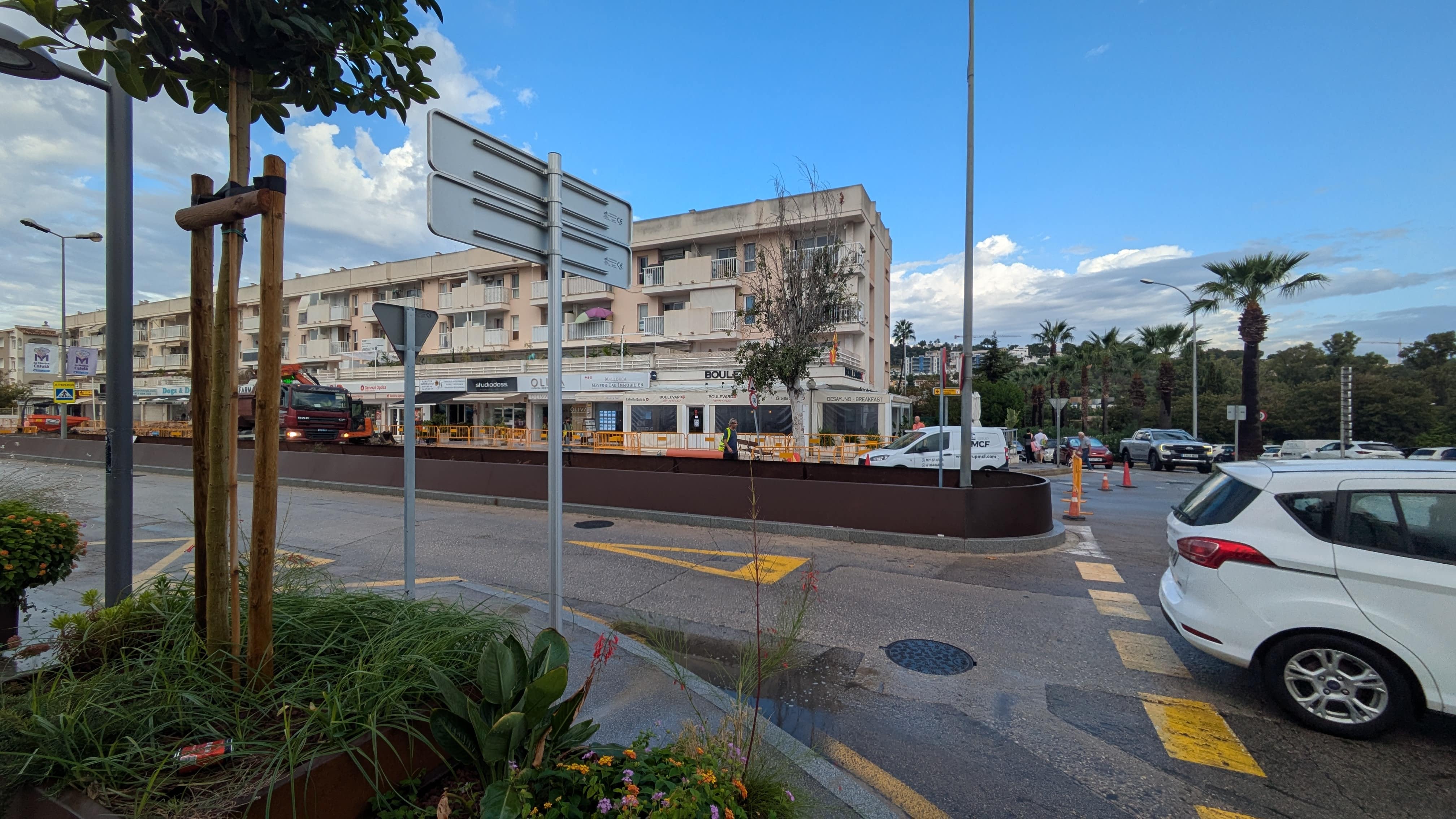 The finished side of Avenida Rei Jaume I with a newly planted tree and central planter, and the works behind