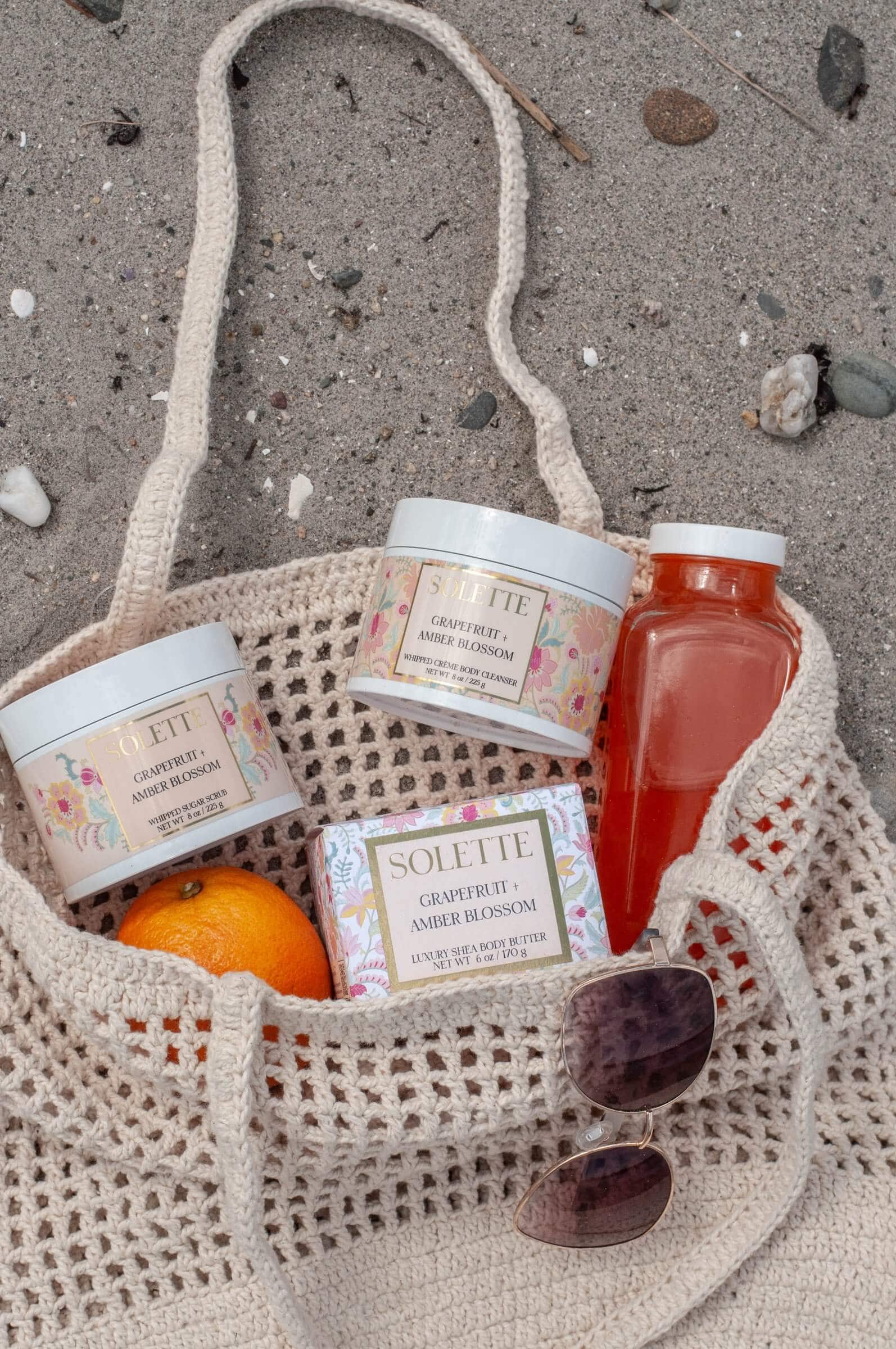 summer self care with body care products in a beach bag on the sand