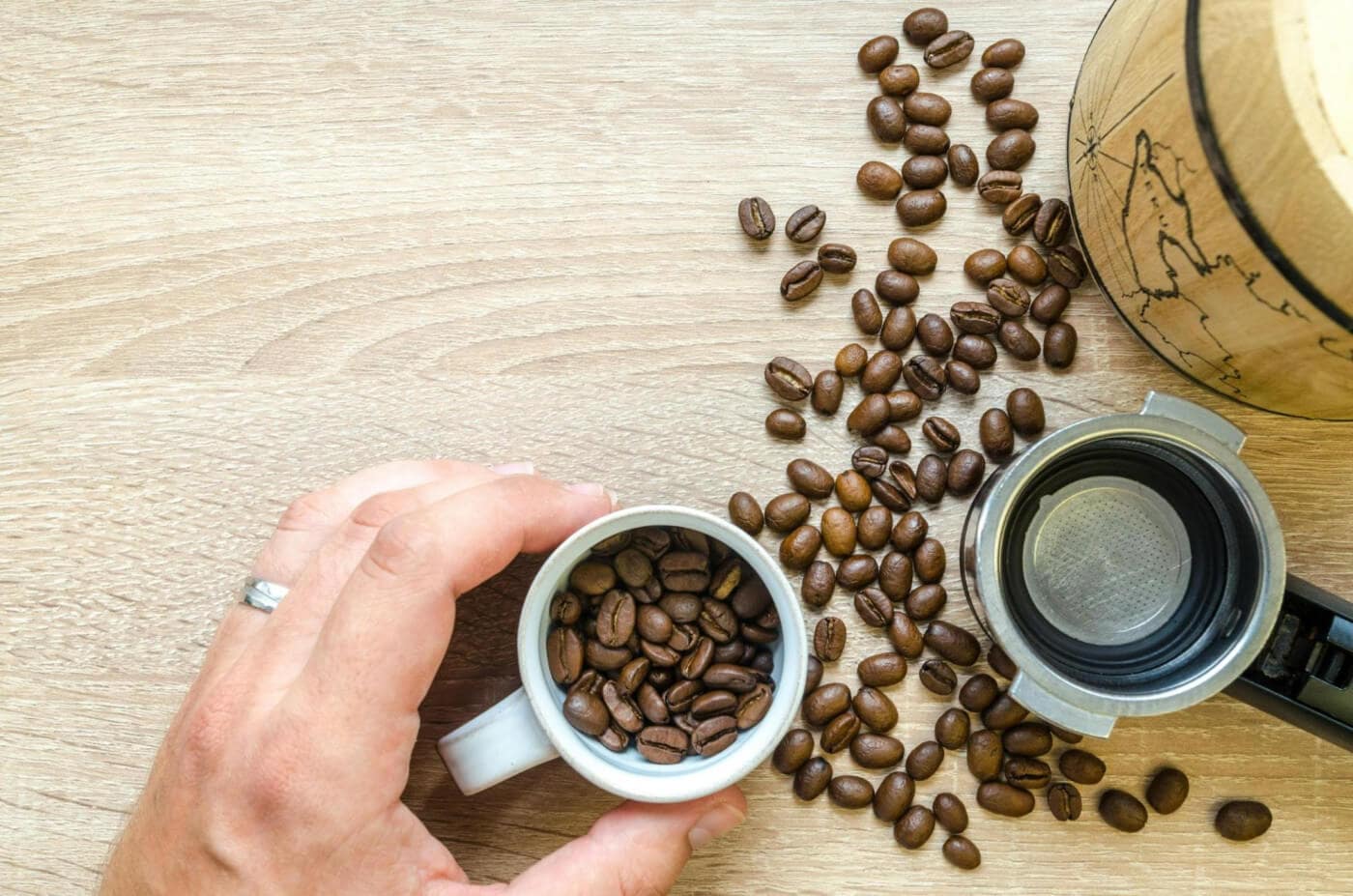 Hand holding a cup of coffee beans.