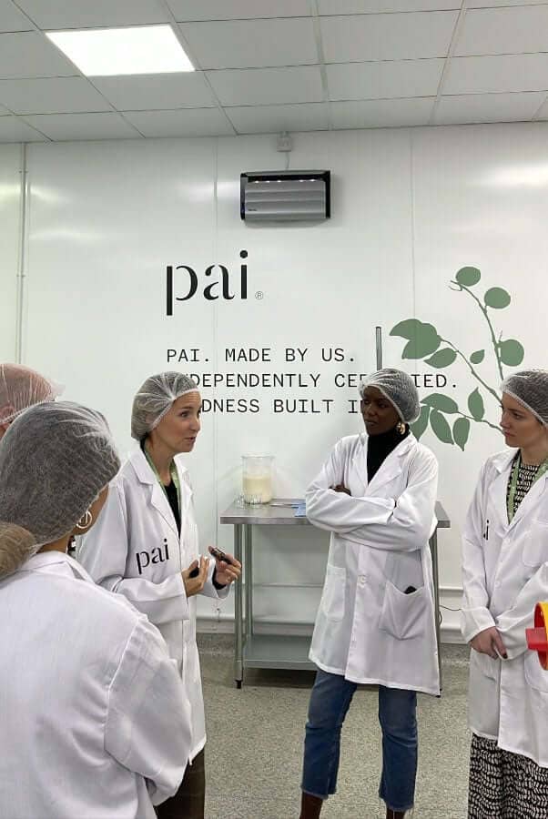Beauty journalists and editors wearing white lab coats during press visit at Pai Skincare laboratory headquarters
