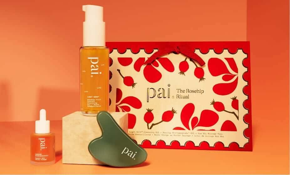 Pai Skincare Rosehip Ritual gift set with orange cleansing oil, red serum, green gua sha tool and rosehip-patterned packaging