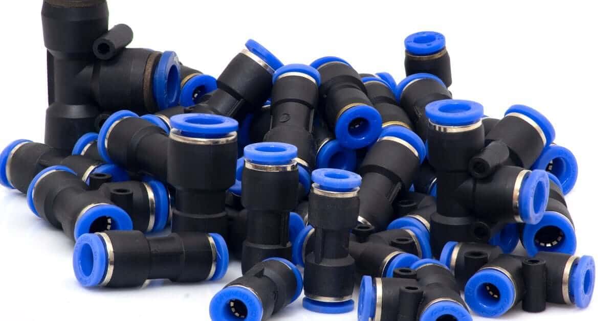 A pile of black pneumatic quick-connect fittings with bright blue collars, including straight, L-shaped, and T-connectors.