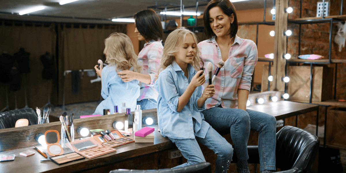 Madre e hija explorando maquillaje para niñas durante un juego creativo en casa