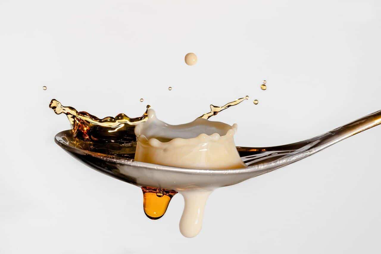 coffee and milk splash on spoon close-up.