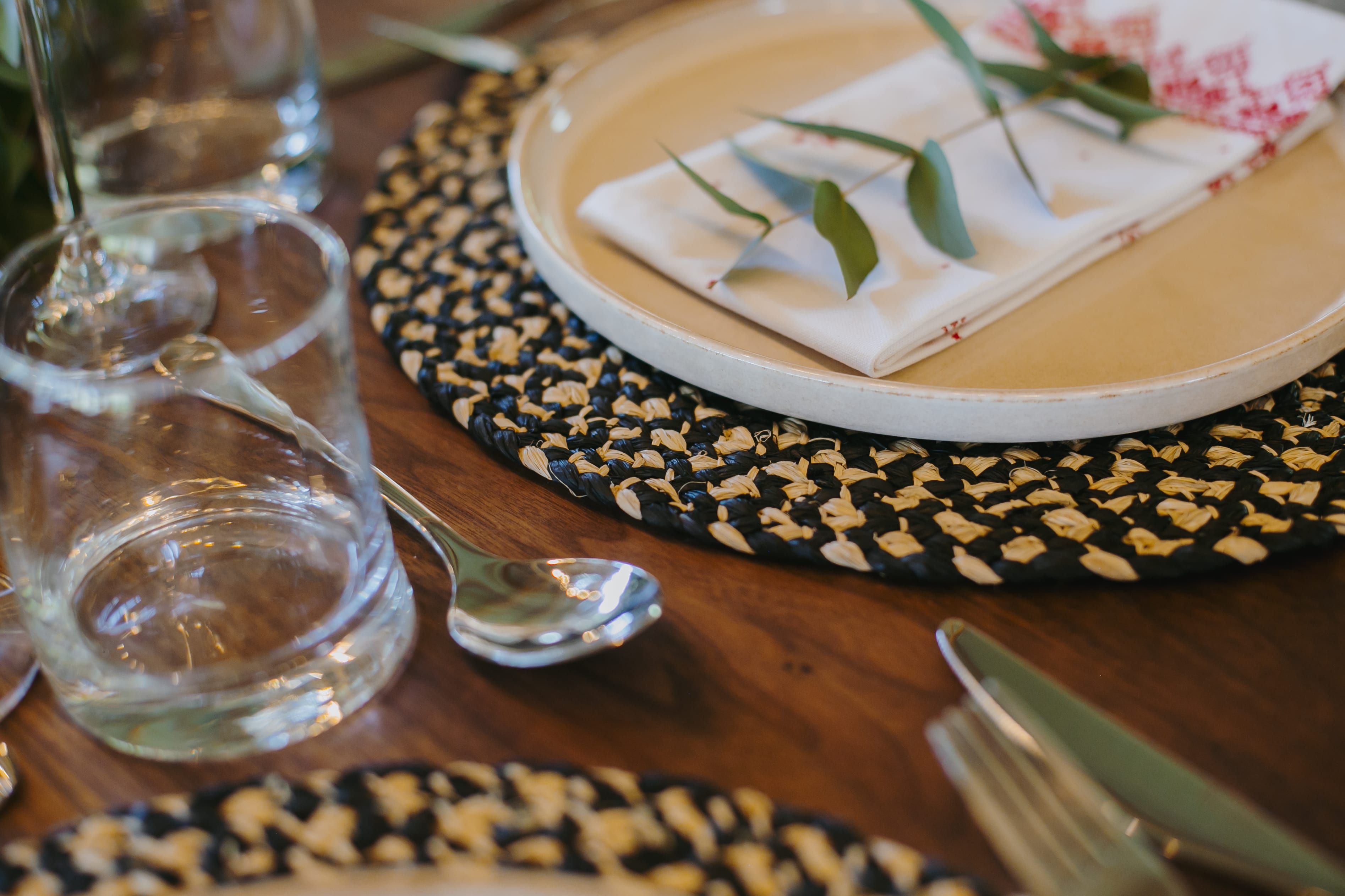 Festive summer table décor with woven placemats, colourful tableware and fresh flowers.