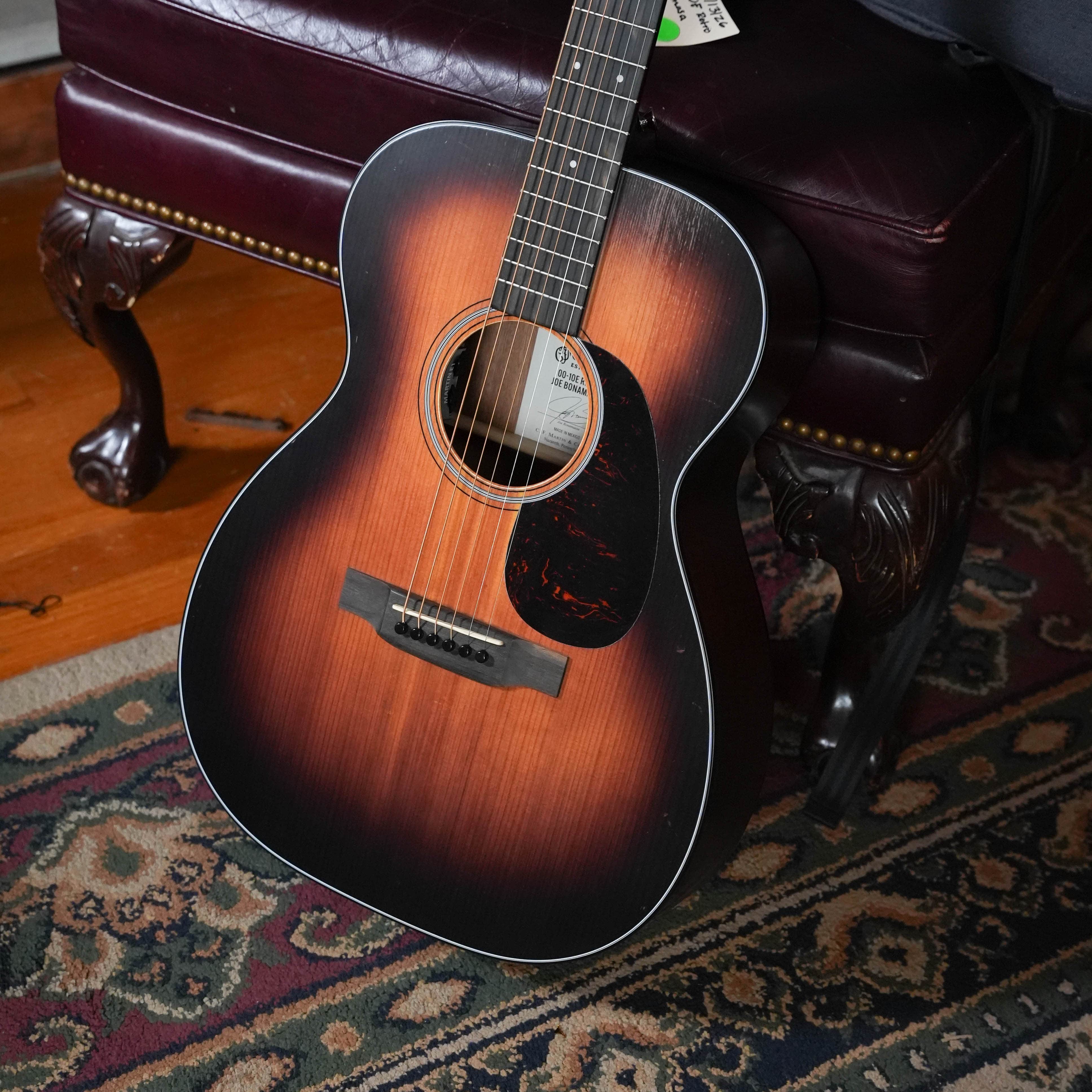 Martin 00-10E Retro Joe Bonamassa in satin 1937 sunburst, leaning on a leather chair
