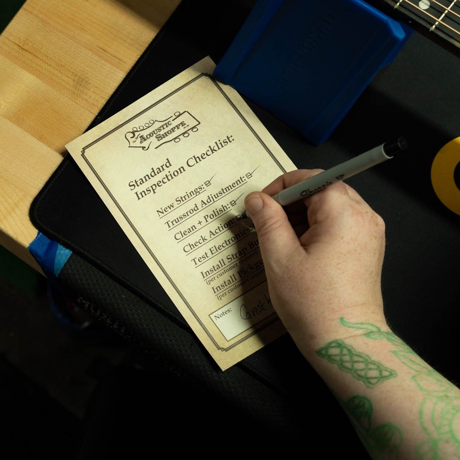 Technician checking off items on a TAS inspection checklist card at the bench