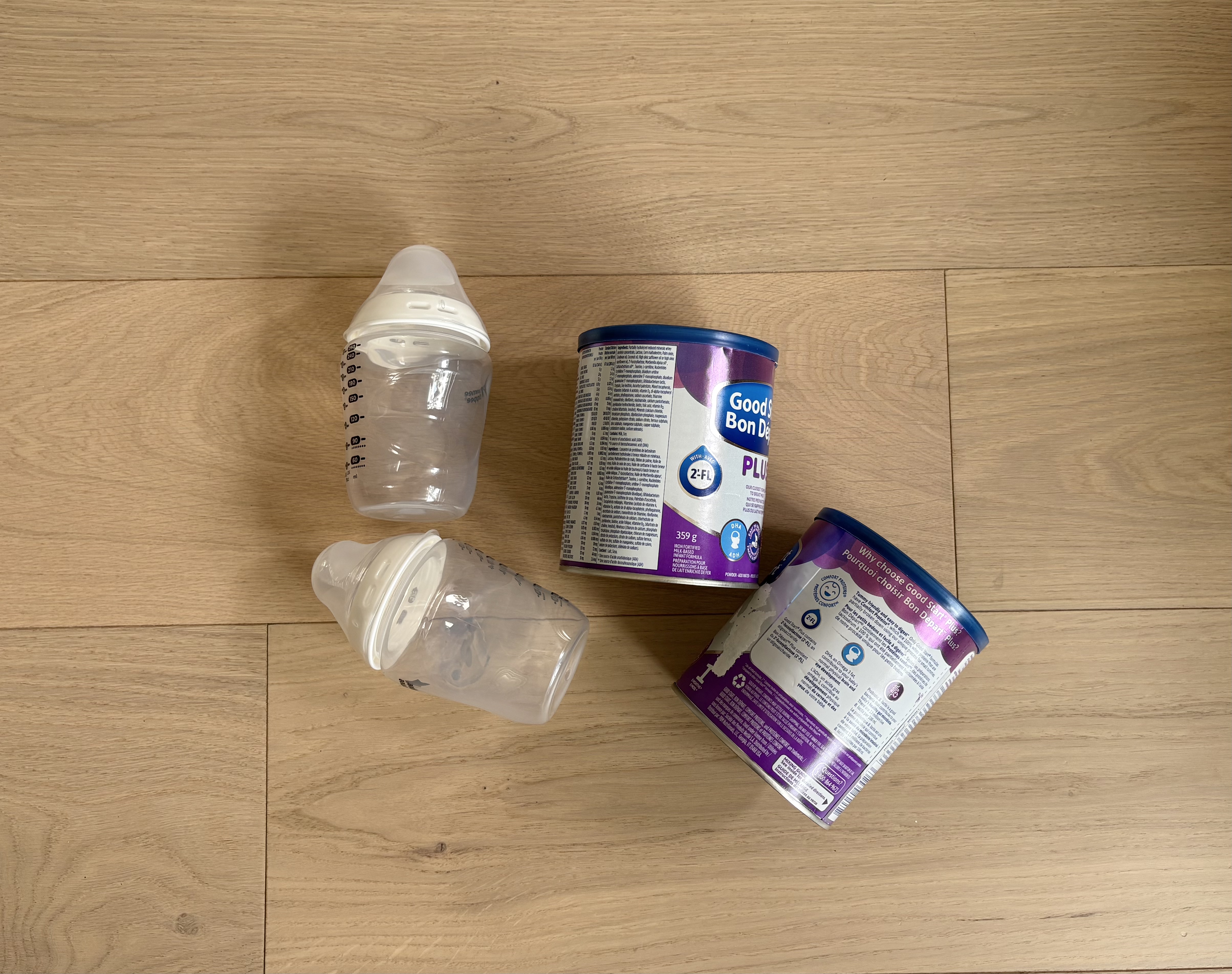 Two baby bottles and two tins of powdered infant formula laid out for travel