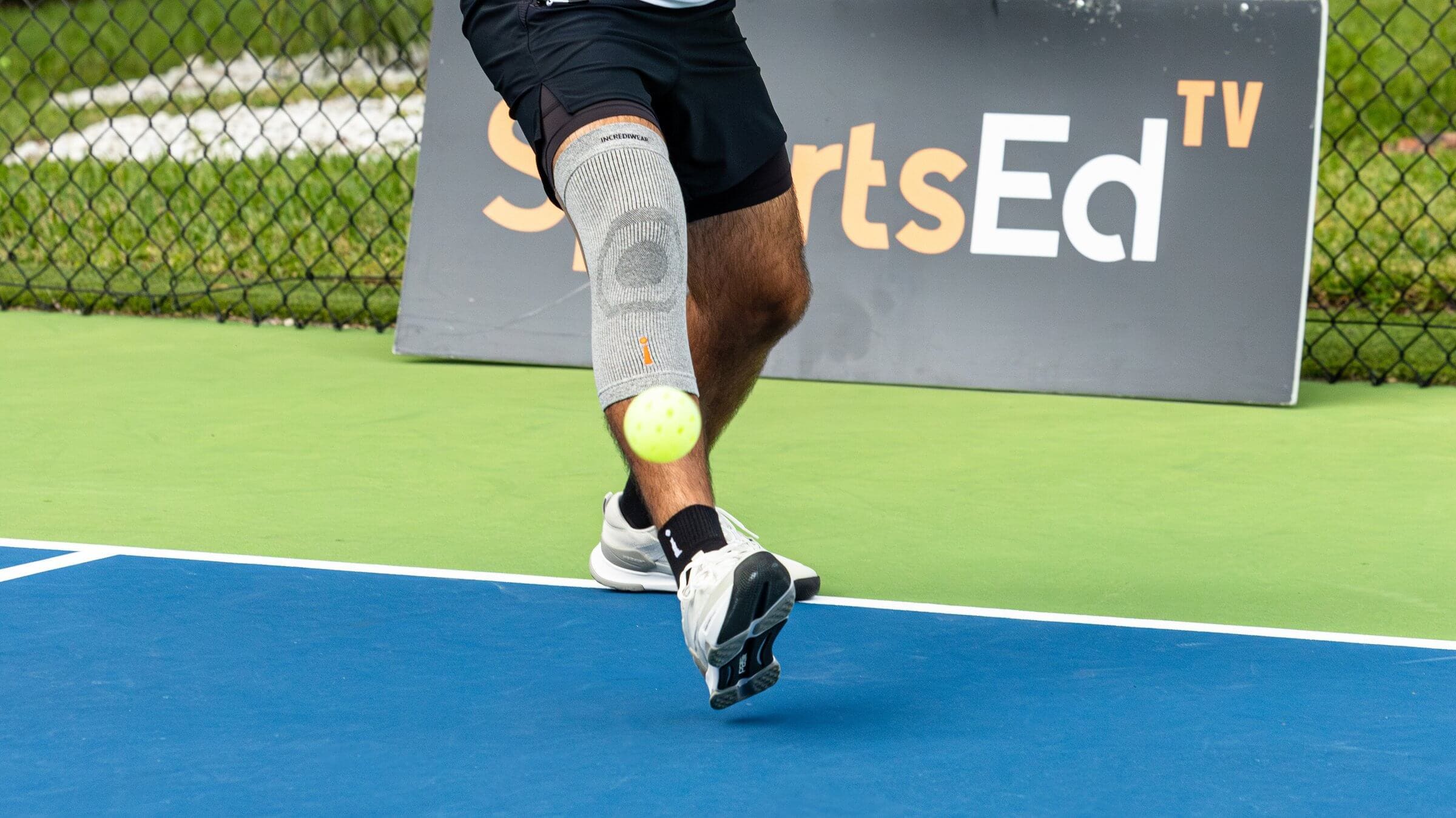 Close up shot of a pickleball mid air and a player behind it