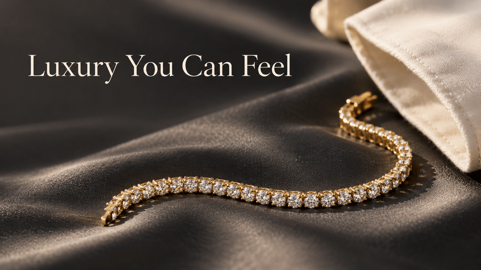 A yellow-gold diamond bracelet curving across charcoal fabric beside an ivory cuff.