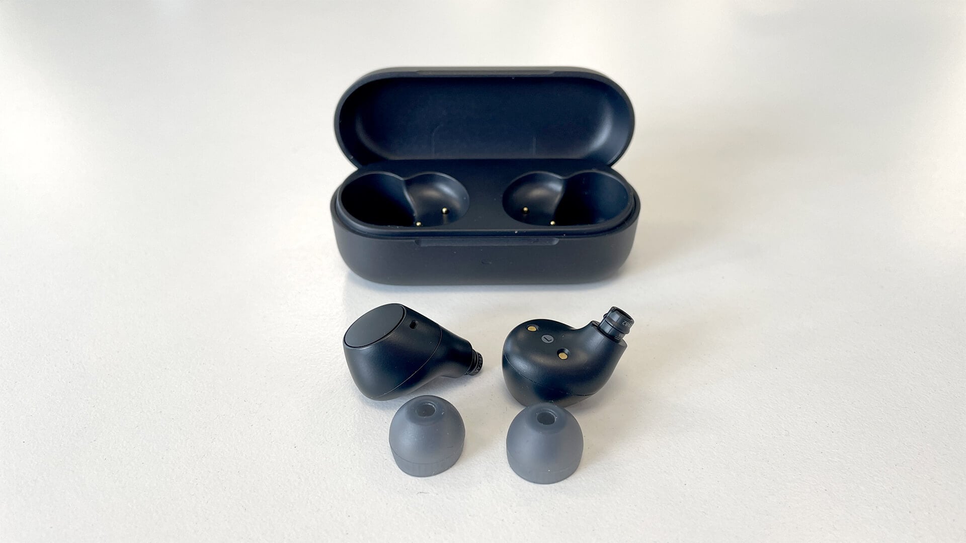 Sony WF-C510 earbuds next to charging case with ear tips on white surface