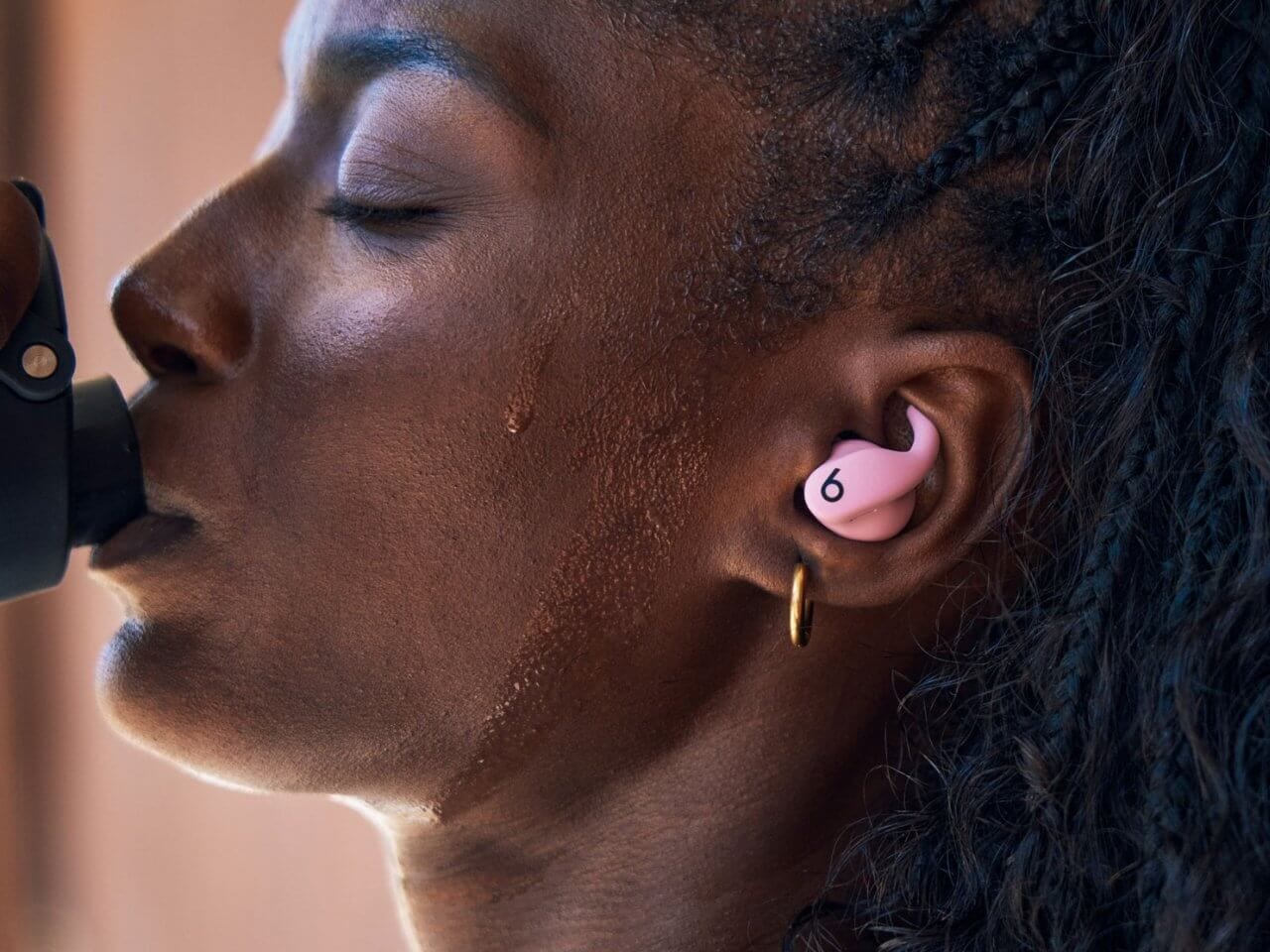Powerbeats Fit earbuds resting on a bright surface