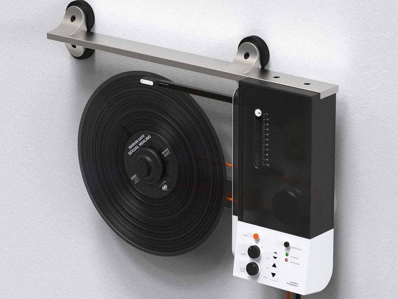 Gold tonearm and black vinyl record on a minimalist white turntable